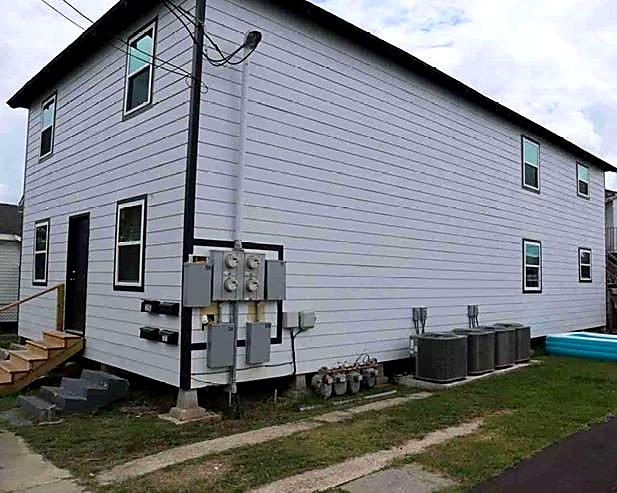 Same two-story apartment building after renovation with new siding, windows, meters and HVAC units
